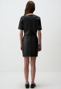 Schwarzes Leder-Minikleid mit einem kurzen Oberteil, kurzen Ärmeln, gerader Passform und einem Rückreißverschluss. Glatte Textur und minimalistisches Design.