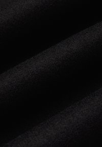 Czarna wełniana tkanina o miękkiej, teksturowanej powierzchni, z subtelnymi fałdami i różnymi odcieniami czerni, idealna do odzieży lub tapicerki.