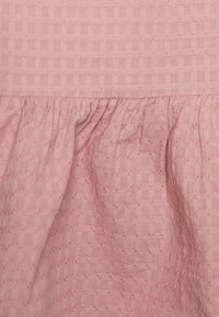 Tecido texturizado rosa com um padrão em grelha e um leve franzido ao longo da borda inferior. Material suave e leve com um ligeiro brilho.