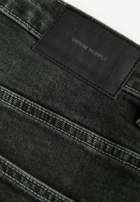 Zwarte denim jeans met een geweven textuur. Voorzien van een rechthoekig stoffen label met "DENIM SUPPLY" in reliëf. Gestikte accenten zichtbaar.