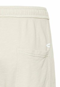 Lys beige sweatpants med strukturstof, elastisk talje, og en sidelomme med hvid logo-detalj.