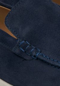 Navy plavi antilop mokasini s kontrastnim šavovima, zaobljenim prstom i glatkom teksturom s minimalnim detaljima.