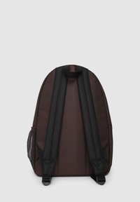 Zaino in tessuto marrone con spallacci neri regolabili, forma arrotondata e tasche laterali in rete. Presenta una maniglia superiore per il trasporto.