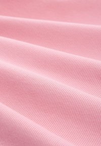 Jasnoróżowa tkanina o prążkowanej strukturze, z delikatnymi fałdami i gładką powierzchnią. Subtelne odcienie koloru podkreślają głębię materiału.