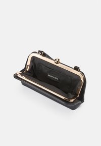 Zwarte clutch met een goudkleurig metalen frame, met een stoffen binnenkant en een klein vakje. Open en toont een platte uitstraling en een gladde textuur.