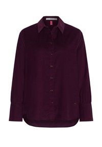 Chemise en velours côtelé violet foncé avec un col pointu, fermeture à boutons et manches longues. Présente un ourlet arrondi et un détail de logo doré subtil.