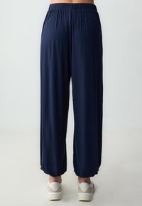 Pantaloni a gamba larga blu navy realizzati in tessuto morbido, dotati di una fascia in vita elasticizzata e una superficie liscia, con orli alla caviglia.