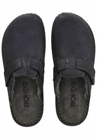 Scarpe slip-on in pelle nera con larghe cinghie, morbida fodera in pelliccia e suole robuste. Presentano dettagli cuciti lungo il bordo.