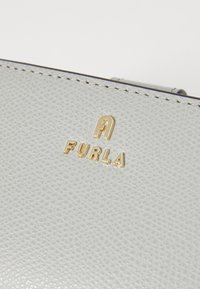 Light gray textured leather purse with a gold-tone "FURLA" logo embossed on the front. Features clean lines and subtle stitching detail.