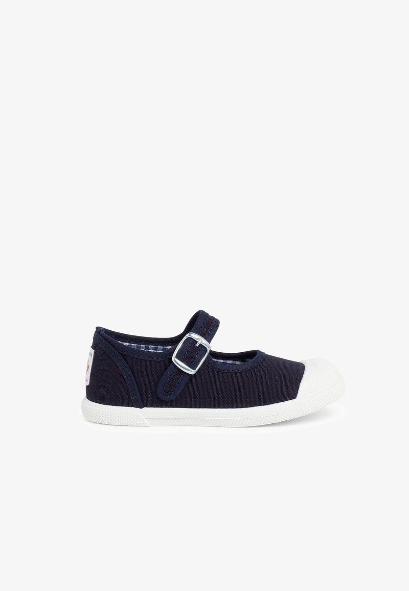 Zapatilla de lona en color navy con puntera de goma blanca, correa ajustable con hebilla de metal y forro a cuadros. Suela plana y forma redondeada.