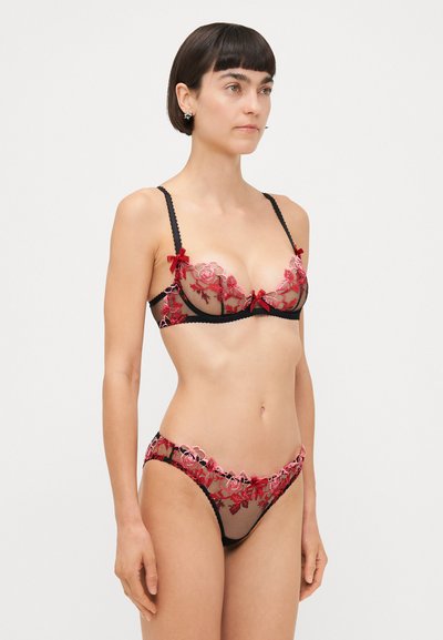 Ensemble de lingerie en dentelle noire avec broderies florales en rouge et rose, accents de nœud et texture transparente, composé d'un soutien-gorge et d'une culotte assortie.