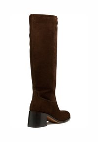 Botas altas de ante marrón hasta la rodilla con un tacón grueso, que presentan una textura suave, punta redondeada y detalles de costura sutiles.