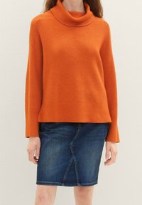 Oranžový žebrovaný rolák s dlouhými rukávy, v kombinaci s tmavě modrou džínovou tužkovou sukni s diagonálním švem.