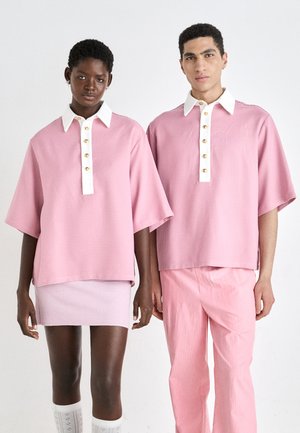 Pink checkered oversized shirts with white collars and golden buttons, paired with a pink skirt and striped trousers. Textured fabric.