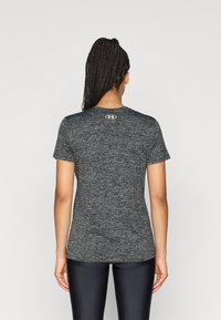 Maglietta da atletica grigia con maniche corte, scollo rotondo e una sottile trama mouliné. Presenta un piccolo logo sul retro.