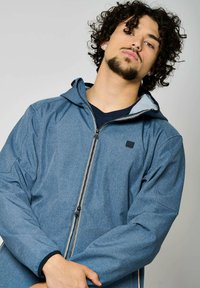 Veste zippée bleu clair avec capuche, fabriquée en tissu texturé. Présente une doublure intérieure contrastante et un petit logo carré sur la poitrine.