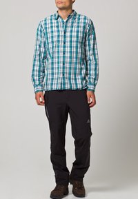 Chemise à manches longues en plaid teal et blanc, associée à un pantalon d'extérieur noir. Les deux vêtements sont en tissu respirant et disposent de fermetures à boutons.