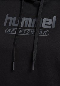 Felpa nera con logo "hummel SPORTSWEAR" in grigio a contrasto. Presenta una tasca frontale e un cordino con estremità nere. Texture morbida.