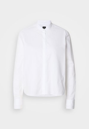 Camisa branca com colarinho, com uma pala frontal, mangas longas e punhos com botões. Feita de tecido de algodão suave com um corte estruturado.