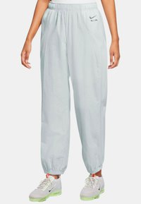 Světle šedé sportovní tepláky s elastickým pasem, bočními kapsami a zúženými manžetami, s malým černým logem "A.I.R.".