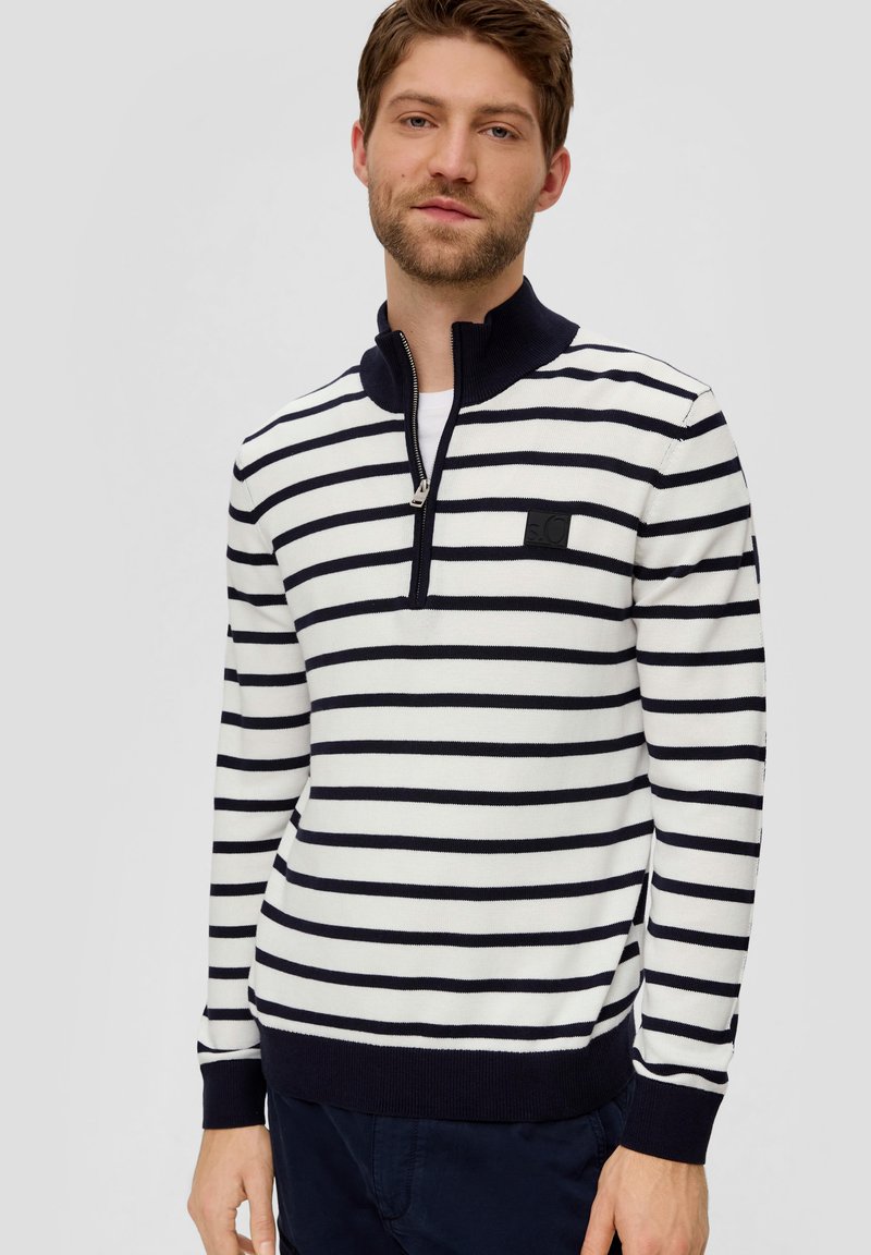Striped sweater in white and navy, featuring a zippered collar, ribbed cuffs, and a logo patch on the chest. Cotton blend material.