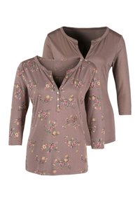 Zwei langärmelige Oberteile in Mauve mit floralen Mustern. Eines verfügt über eine Knopfleiste und das andere hat eine Schlüssellochöffnung am Ausschnitt.