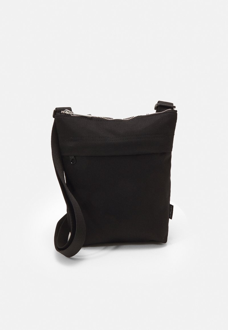 Black canvas crossbody bag with a zip closure, flat design, adjustable strap, and a small front pocket. Textured fabric with minimalist detailing.