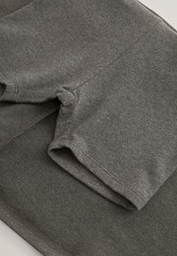 Gros plan sur un short en tissu gris plié montrant une texture douce et des coutures détaillées.