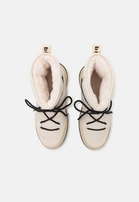 Crème-kleurige winterlaarzen met zwarte veters, nep bontvoering en een logo-tag op de hiel. Ronde vorm met een gestructureerde zool.