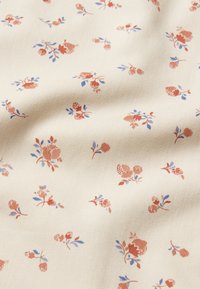 Blomstrete stoff med kremfarget bakgrunn, med et repeterende mønster av små oransje og blå blomster med grønne blader. Glatt tekstur.