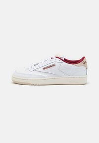 Weiße Ledersneaker mit roten und beigen Akzenten, ausgestattet mit einer strukturierten Gummisohle, Schnürsenkeln und einem aufgenähten Logolabel an der Seite.