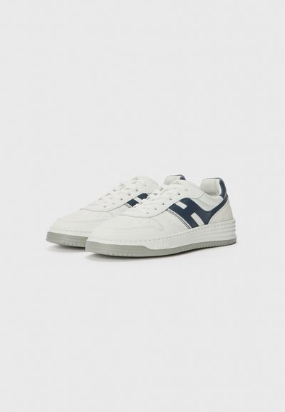Sneakers bianchi in pelle con accenti blu navy e dettagli perforati. Presentano una suola in gomma testurizzata e lacci piatti.
