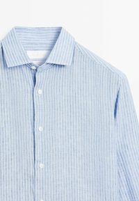 Camicia a righe blu chiaro con colletto classico, maniche lunghe e bottoni bianchi. Il tessuto ha una finitura texturizzata con sottili linee verticali.