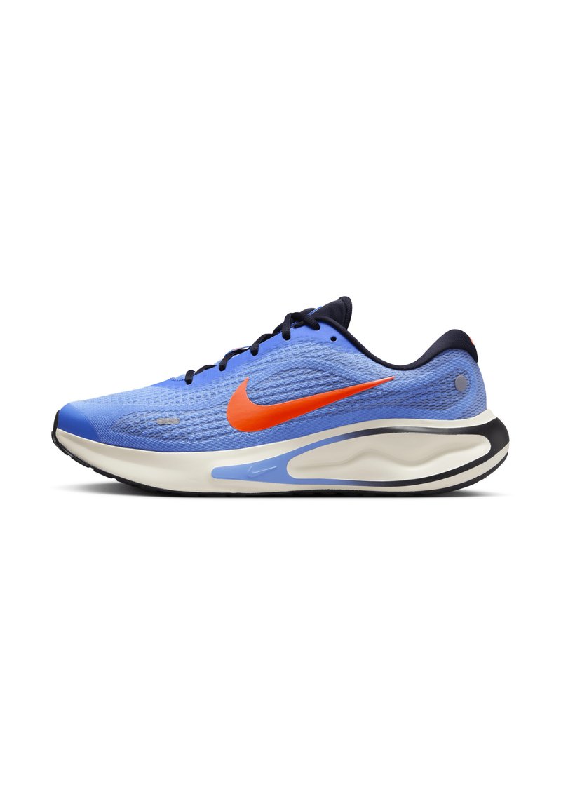 Modrá běžecká bota s oranžovým logem Nike, černými tkaničkami, polstrovanou bílou podrážkou a černou venkovní podrážkou, zobrazená z levé strany.