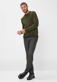 Olijfgroene longsleeve sweatshirt met ronde hals, gecombineerd met donkergrijze gestructureerde broek en zwarte veterschoenen. Eenvoudige en aansluitende stijl.