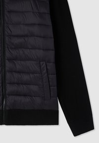 Gilet invernale nero con parte frontale trapuntata e testurizzata e maniche lisce. Dotato di chiusura con zip e tasca laterale, orlo a coste testurizzate.