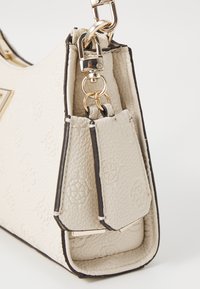 Borsa a tracolla beige texture con hardware dorato, rifiniture nere e tracolla removibile. Presenta motivi floreali in rilievo sulla superficie.