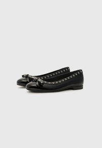 Black patent leather ballet flats with bow detail, silver grommets around the opening, low heel, and rounded toes. Smooth texture.