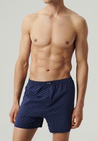Granatowe bokserki z drobnym wzorem, elastyczny pasek w talii i zapięcie na guzik z przodu. Wykonane z miękkiego materiału, zaprojektowane z myślą o komforcie.