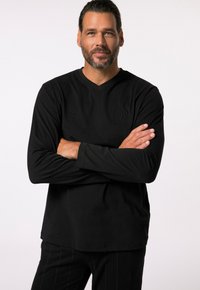 Zwarte lange mouwen V-hals shirt van zachte stof, met subtiele logo borduring op de borst, gecombineerd met gestreepte zwarte broek.
