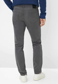 Grijze katoenen broek met een slim fit, met achterzakken en een gestructureerde afwerking, gecombineerd met witte sneakers en een blauwe trui.