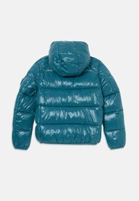 Teal pufferjacka med huva, glänsande yta, quiltat mönster och elastiska mudd. Har dragkedjestängning och är tillverkad av lätt material.