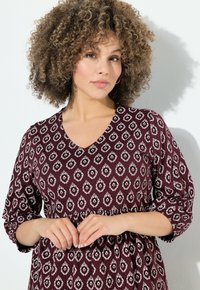 Maroon sukienka w wzory w diamenty, z dekoltem w serek i rękawami o długości trzech ćwierci, wykonana z miękkiego materiału o lekkiej, zwiewnej teksturze.