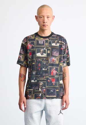 Graphic t-shirt featuring a collage of vintage televisions displaying basketball imagery, predominantly black with colorful accents and a crew neck.
