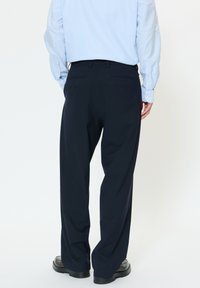 Marynarskie spodnie o luźnym kroju, wykonane z gładkiej tkaniny, z tylnymi kieszeniami i pasem z szlufkami na pasek.