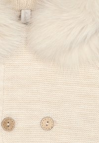 Suéter de punto color crema con un suave cuello de piel sintética, dos botones decorativos de color marrón claro y un patrón texturizado sutil.