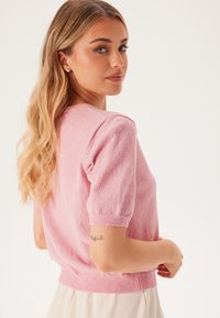 Kortärmad, ljusrosa tröja i en texturerad tyg, med rund halsringning och ribbad nederkant, designad för en figurnära passform.