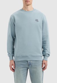 Light blue sweatshirt with a crew neckline, ribbed cuffs and hem, featuring a small printed logo on the left chest side.