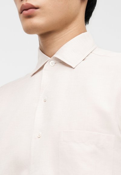 Ροζ ανοιχτό ροζ πουκάμισο με κοντά μανίκια και μυτερό γιακά,με κουμπιά μπροστά και τσέπη στο στήθος. Υφή υφάσματος με απαλό φινίρισμα.