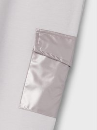 Țesătură gri cu un detaliu de buzunar lucios de culoare violet deschis. Buzunarul are un capac cu o textură netedă și cusături îngrijite.